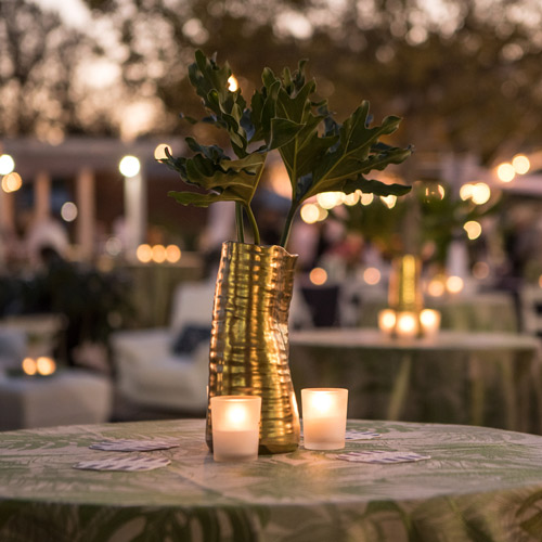 a view of one of the tables set up at the event showcasing a green plant in a golden vase