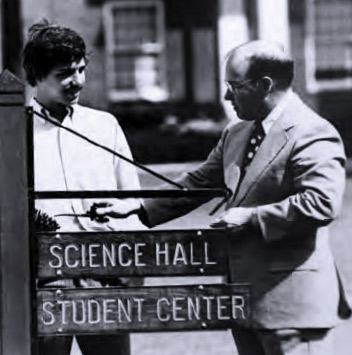 photo from 1965, two men standing around a street sign that reads: Science Hall, Student Center