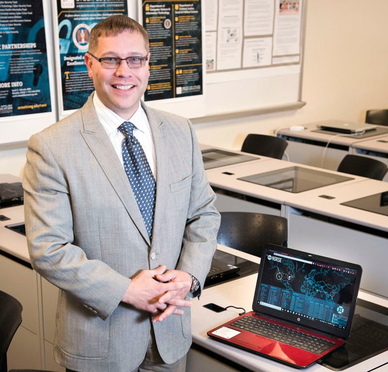 CACE Director Scott C. Scheidt CACE Director Scott C. Scheidt standing next to a laptop in a classroom setting