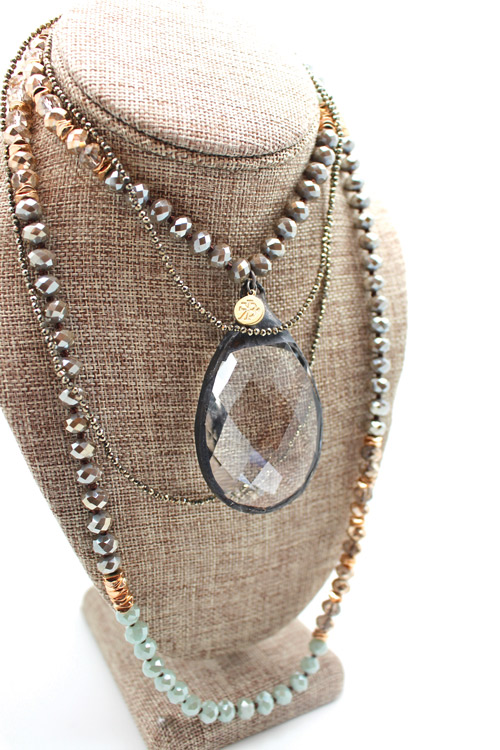 a four layer gold and silver necklace with a large clear crystal in the middle