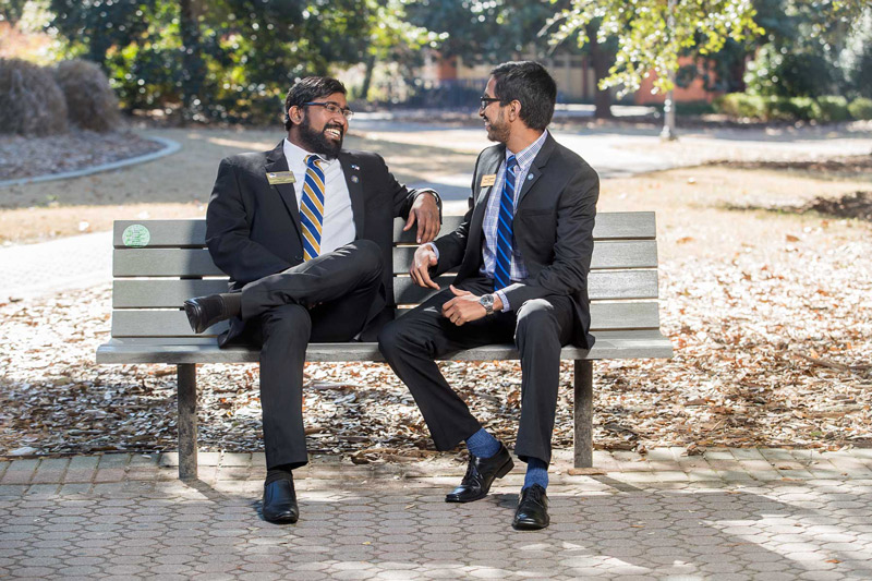 Dylan John and Nipuna Ambanpola sitting together on a bench talking with each other and laughing