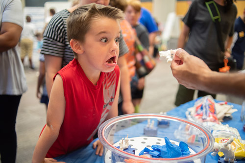 boy looking surprised while viewing a toy figure