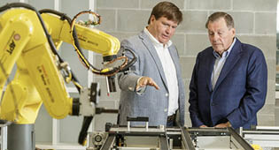 Bill Crider III (left) and Billy Crider Jr. (right) inspect automation equipment at the Engineering and Research Building.