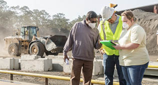 Atin Adhikari, Ph.D, (L) associate professor in the Jiann-Ping Hsu College of Public Health, and Master of Public Health student Victoria Clower review dust particle readings with the construction foreman.