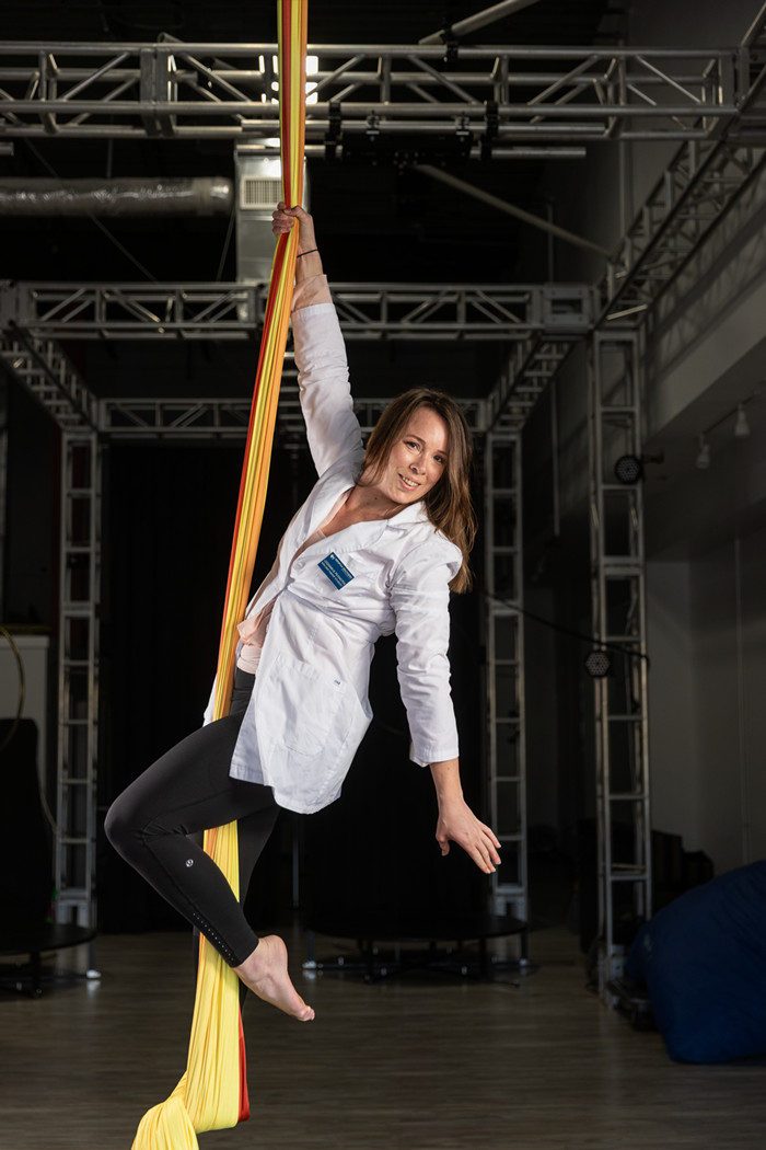 Leighann-Pilkington wearing her nurse's lab coat while suspended in the air on an aerobics dance ribbon.
