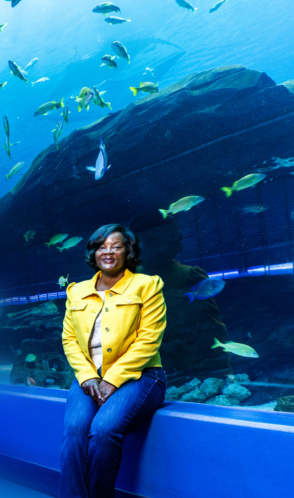 Tammie Williams sitting in front of an underwater ocean life tank at the Georgia Aquarium.